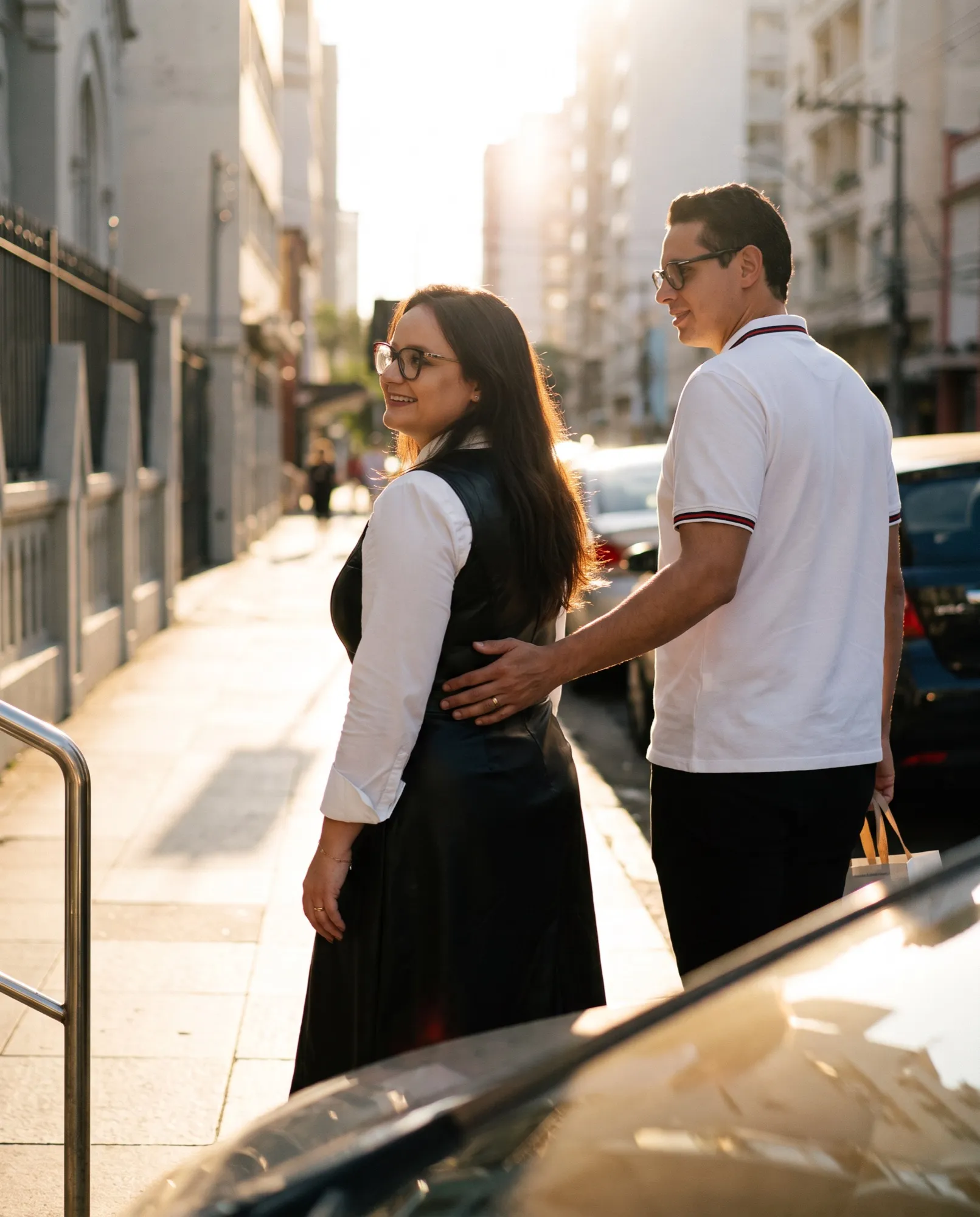 Casal saindo da Ótica Kirsch com a sacola da loja, no fim de tarde no Centro de Novo Hamburgo